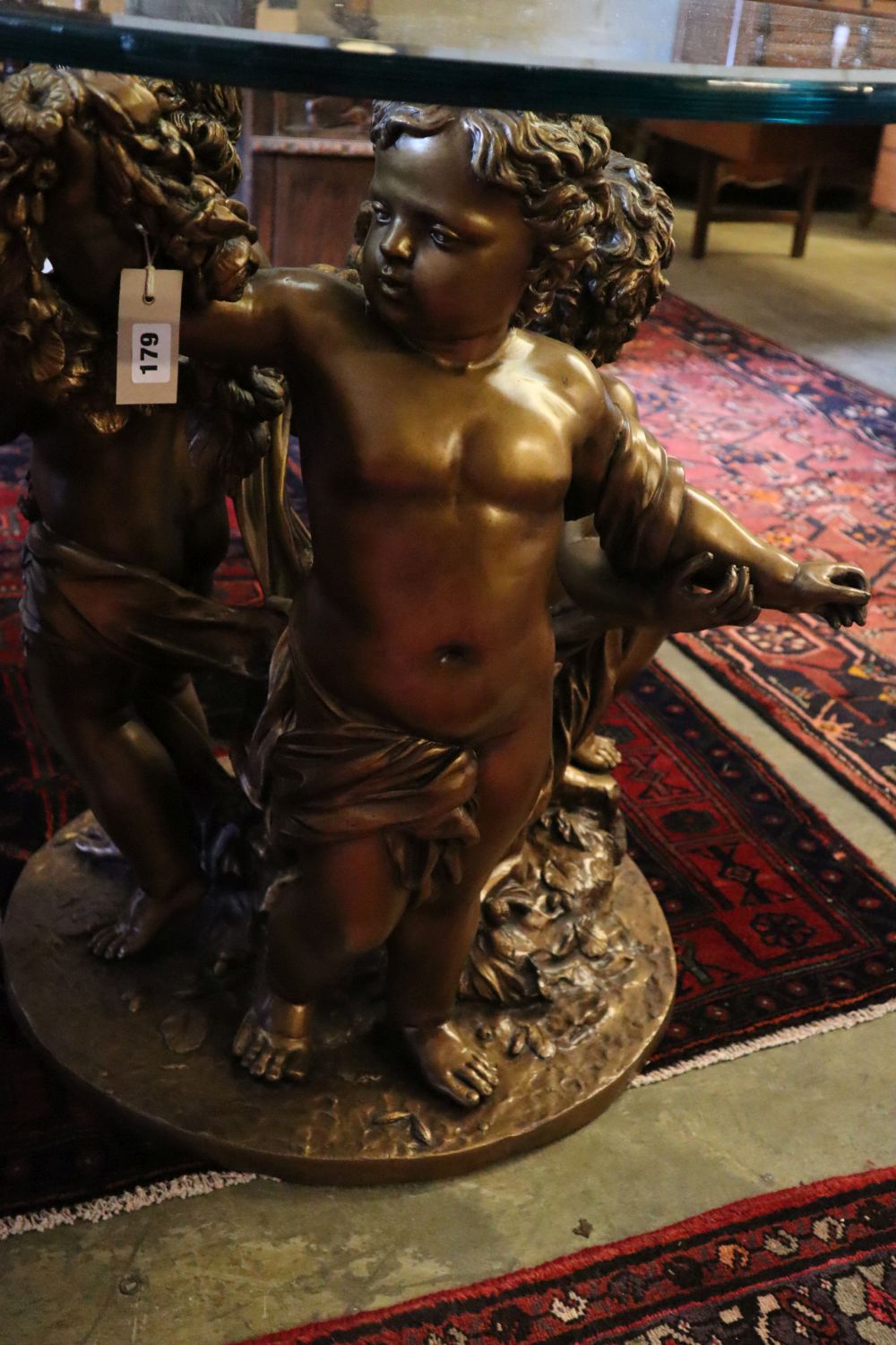 A cast gilt metal glass top cherub centre table, 81cm diameter